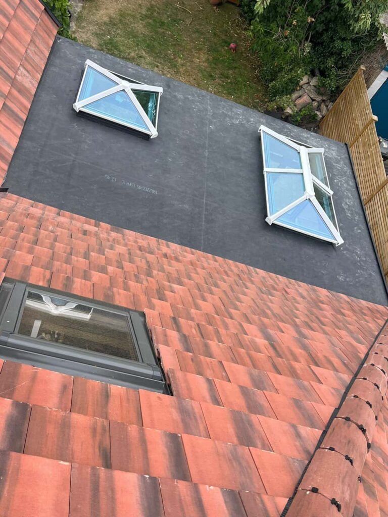 This is a photo taken from the roof ridge looking down a tiled pitched roof on to a flat roof. Works carried out by LJ Roofing South Cerney